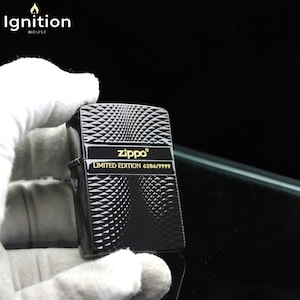 May include: Black Zippo lighter with a geometric pattern and gold text. The lighter features the text "Zippo" and "LIMITED EDITION 6286/9999". The top left corner of the image has the text "Ignition House".