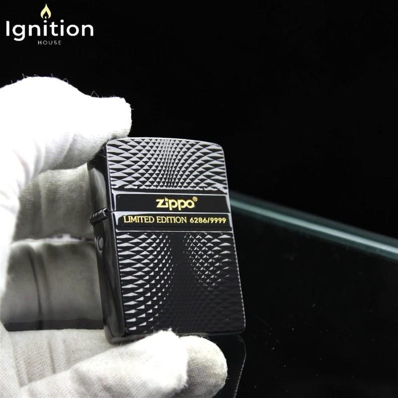 May include: Black Zippo lighter with a geometric pattern and gold text. The lighter features the text "Zippo" and "LIMITED EDITION 6286/9999". The top left corner of the image has the text "Ignition House".