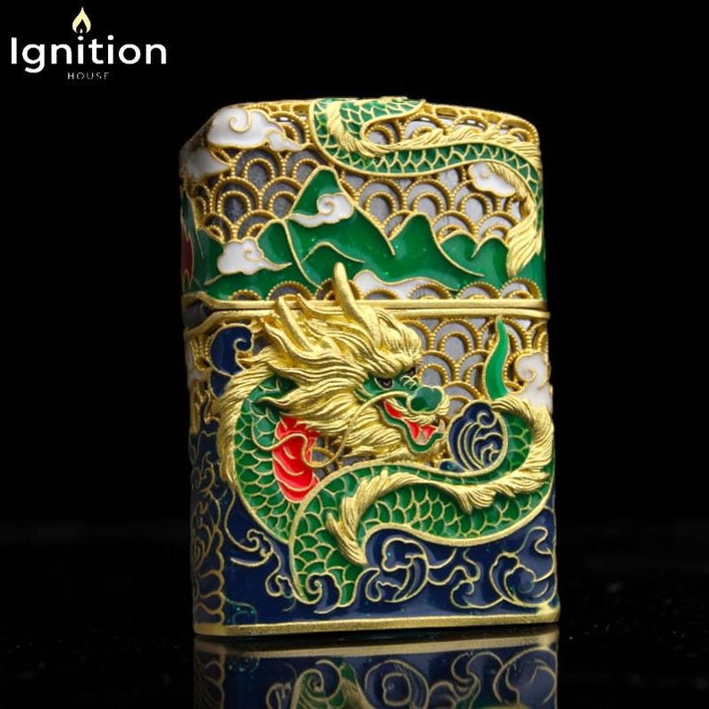 May include: A decorative lighter with a detailed dragon design. The lighter features a gold-colored dragon with green, red, and blue accents. The top of the lighter has a mountain and cloud design. The text "Ignition House" is in the upper left corner.