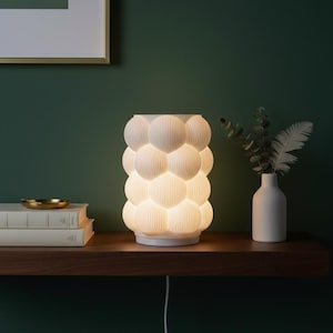 Könnte beinhalten: Eine weiße Keramik-Tasse mit schwarzem Henkel und dem Text "But First, Coffee" in schwarzer, fetter Schrift. Die Tasse steht auf einer weißen Oberfläche.