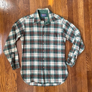 May include: A green, white, and red plaid flannel shirt with a button-up front and long sleeves. The shirt has a label that reads "Patagonia" in blue.
