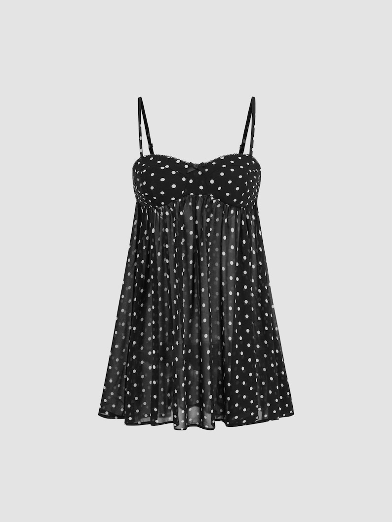 K&ouml;nnte beinhalten: Schwarzes Camisole mit wei&szlig;en Polka Dots und d&uuml;nnen Tr&auml;gern. Das Oberteil im Babydoll-Stil hat einen Sweetheart-Ausschnitt und einen flie&szlig;enden, halbtransparenten Stoff. Das Kleidungsst&uuml;ck hat ein gerafftes Oberteil und einen ausgestellten Rock.