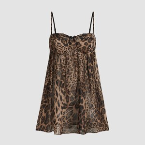 K&ouml;nnte beinhalten: Ein Babydoll-Kleid mit Leopardenmuster, d&uuml;nnen schwarzen Tr&auml;gern und einer kleinen Schleife an der Brust. Das Kleid hat ein gerafftes Oberteil und einen flie&szlig;enden, durchsichtigen Rock. Der Animal-Print ist in Braun- und Schwarzt&ouml;nen gehalten.