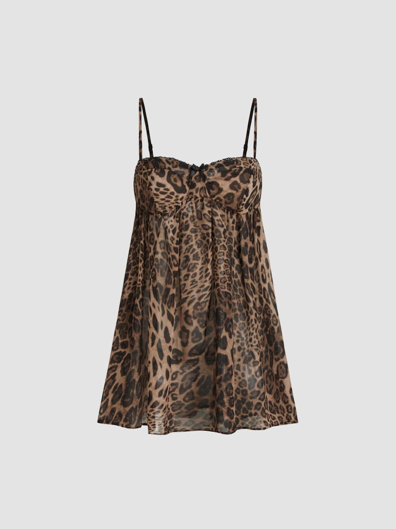 K&ouml;nnte beinhalten: Ein Babydoll-Kleid mit Leopardenmuster, d&uuml;nnen schwarzen Tr&auml;gern und einer kleinen Schleife an der Brust. Das Kleid hat ein gerafftes Oberteil und einen flie&szlig;enden, durchsichtigen Rock. Der Animal-Print ist in Braun- und Schwarzt&ouml;nen gehalten.