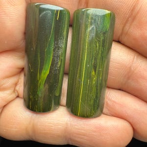 May include: Two rectangular cabochons with a smooth, polished finish. The stones feature a deep forest green base colour with prominent, swirling vertical streaks of bright lime green and yellow, creating a marbled, organic appearance.
