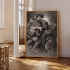 May include: A framed black and white art print depicting a person riding a large wolf with its mouth open, revealing sharp teeth. The scene is set against a bright circular moon, rendered in a detailed charcoal style with dramatic shading.