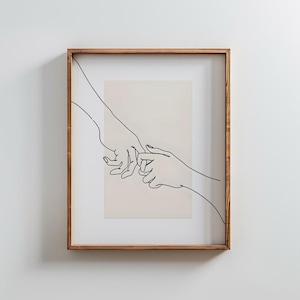 May include: A framed art print featuring a minimalist line drawing of two hands holding each other's index fingers. The artwork is rendered in black lines on a beige background, encased in a wooden frame.