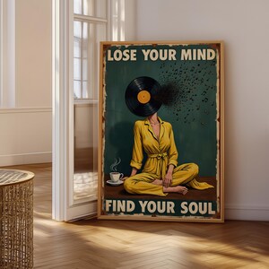 May include: A rectangular wall poster with a dark green background featuring a person in a yellow jumpsuit sitting cross-legged with a vinyl record for a head. Musical notes emerge from the record. Text reads LOSE YOUR MIND and FIND YOUR SOUL.