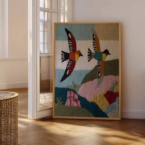 Puede incluir: Una pieza de arte mural rectangular con un diseño textil de mechones de dos aves en vuelo sobre un paisaje. Las aves tienen alas rojas, amarillas, negras y azules. El paisaje inferior incluye secciones texturizadas en tonos verde, rosa y rojo.