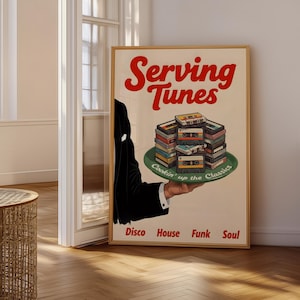 May include: A framed poster with the text "Serving Tunes" in red, featuring a stack of cassette tapes on a green plate. The poster also includes the words "Disco House Funk Soul".