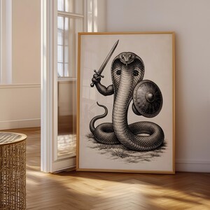 Può includere: Una stampa artistica da parete incorniciata che presenta un'illustrazione a inchiostro in bianco e nero di un cobra in posizione eretta. Il serpente ha braccia muscolose e tiene una spada in una mano e uno scudo rotondo nell'altra, su sfondo bianco sporco.