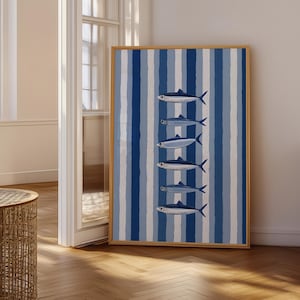 May include: A rectangular wall art print in a light wood frame featuring a vertical pattern of alternating dark blue, light blue, and white stripes. Six stylized fish are arranged in a single vertical column, centered over the striped background.