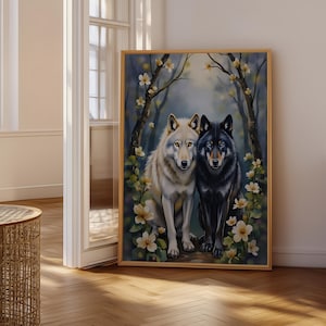 May include: A rectangular wall art print in a light wood frame featuring a white wolf and a black wolf sitting side by side. The wolves are surrounded by dark tree trunks and delicate white flowers with yellow centres against a soft blue background.