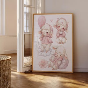 Può includere: Una stampa artistica incorniciata con tre illustrazioni di agnelli bianchi soffici che indossano felpe con cappuccio e sciarpe rosa. Un agnello tiene un palloncino rosa, un altro una tazzina e il terzo dorme su un cuscino. Cuori rosa e un fiore decorano la scena.