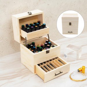 May include: A light-colored wooden essential oil storage box with multiple compartments and a drawer. The box is open, revealing numerous small glass bottles with colorful lids. The box has a metal clasp and handle.