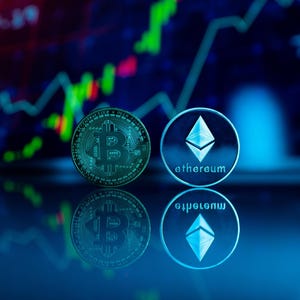 May include: Two cryptocurrency coins, Bitcoin and Ethereum, are displayed against a backdrop of a stock market graph. The Bitcoin coin is gold-colored, while the Ethereum coin is silver. The background is a dark blue with green and red lines.