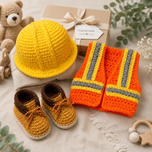 Peut inclure: Un ensemble de construction au crochet comprenant un casque jaune vif, un gilet de sécurité orange avec des bandes grises réfléchissantes et une paire de bottes de travail marron et beige avec lacets. Une boîte cadeau avec l'étiquette Handmade with love.
