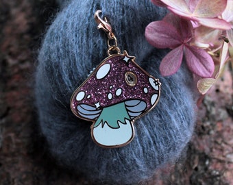 May include: A gold-tone mushroom charm with pink glitter and white dots. The charm has a green stem and a gold-tone clasp.