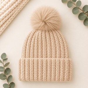 Pu&ograve; includere: Un berretto in maglia beige caratterizzato da una spessa trama a coste e un ampio risvolto ripiegato. Il cappello &egrave; sormontato da un grande e soffice pon-pon in pelliccia sintetica beige abbinato, che conferisce un aspetto morbido e uniforme.