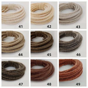 May include: Nine hair scrunchies in shades of cream, beige, brown, and rust. Each scrunchie is made from a soft, velvety fabric and is coiled into a circular shape. Numbers 41 to 49 are printed on the image.