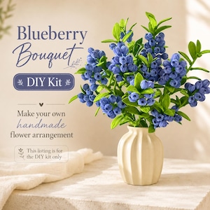 Peut inclure: Un bouquet de myrtilles fait à la main dans un vase crème. L'arrangement présente des grappes de baies bleues avec des feuilles vertes. Le texte sur l'image indique "Blueberry Bouquet DIY Kit. Make your own handmade flower arrangement."