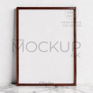Może przedstawiać: Prostokątna drewniana rama w kolorze ciemnobrązowym z białym wnętrzem. Rama umieszczona na tle teksturowanej białej ściany. Tekst na ramie: "Frame Mockup 4K" i "Hero Frame Collection".