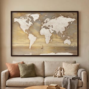 Könnte beinhalten: Ein gerahmtes Weltkarten-Wandbild mit cremefarbenen Landmassen vor einem sanften, goldfarbenen Ozeanhintergrund. Die Karte enthält den Text "OUR TRAVEL MAP" in der unteren linken Ecke sowie eine kleine Illustration eines Segelboots.