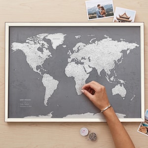 May include: A framed world map with a dark gray background and silver-colored landmasses. The map features the text "QUIET PASSAGES" in the lower-left corner, along with a legend listing "Paths Walked" and "Destinations to Seek".