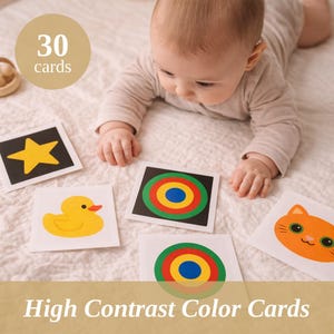 Może przedstawiać: Niemowlę otoczone kartami o wysokim kontraście kolorów z żółtą gwiazdą, kaczką, kotem i koncentrycznymi okręgami. Karty leżą na białej powierzchni. Obraz zawiera tekst "30 kart" i "High Contrast Color Cards".