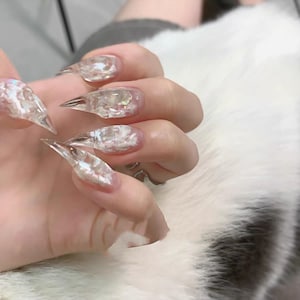 Könnte beinhalten: Eine weiße Keramik-Tasse mit schwarzem Henkel und dem Text "But First, Coffee" in schwarzer, handschriftlicher Schrift. Die Tasse steht auf einer weißen Oberfläche.