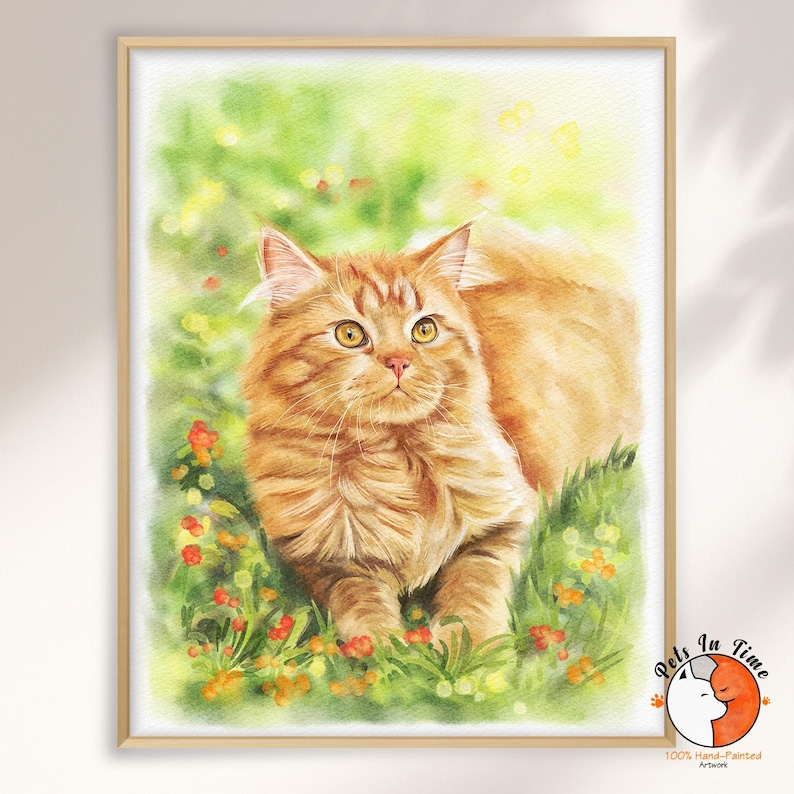May include: A watercolor painting of a fluffy orange tabby cat with yellow eyes, positioned in a field of green grass and small red flowers. The artwork is framed in a light wood frame and features a small logo in the corner with the text Pets In Time.