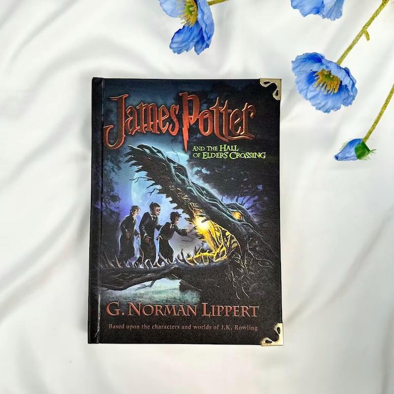 May include: A hardcover book titled "James Potter and the Hall of Elders Crossing" by G. Norman Lippert. The cover features a dark illustration of three figures and a large, shadowy creature. Gold corner protectors are visible.