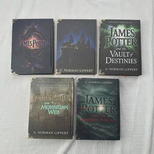 May include: Five hardcover books with gold corner accents are displayed. The book titles include "James Potter" and "The Vault of Destinies". The covers feature dark colors, including black, green, and grey, with various graphics and text.