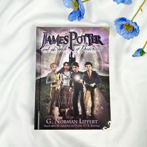 May include: A hardcover book titled "James Potter and the Vault of Destinies" featuring four young characters on the cover. The book's cover has a dark, fantasy-themed illustration with the author's name and a tagline at the bottom.