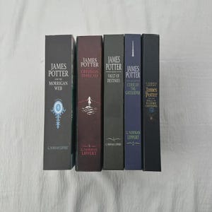 May include: A collection of hardcover books with titles including "James Potter and the Morrigan Web" and "James Potter and the Hall of Elders Crossing." The spines are various colors, with the author's name at the bottom.