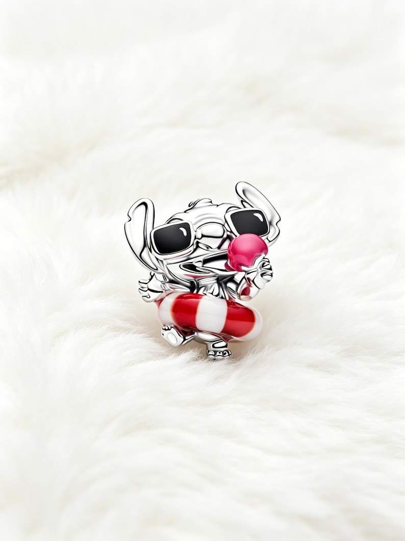 May include: A silver charm depicting a cartoon character wearing sunglasses and holding a pink ice cream cone. The character is also wearing a red and white striped life preserver. The charm is set against a white, fluffy background.