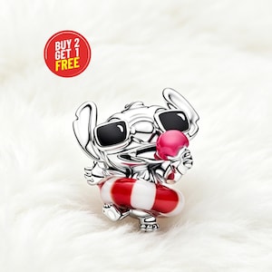 May include: A silver charm featuring a cartoon character wearing sunglasses and a red and white striped floatie. The character is holding a pink ice cream cone. A red circle with the text "BUY 2 GET 1 FREE" is in the upper left corner.