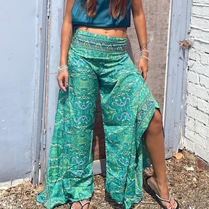 May include: Wide-leg pants featuring a vibrant green and teal paisley pattern with a wide, fold-over waistband. The pants have a loose, flowing silhouette with a high side slit on the left leg, crafted from a lightweight, patterned fabric.