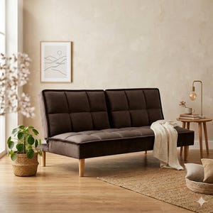 May include: A brown futon sofa with a tufted design and wooden legs. A white blanket is draped over the extended chaise. The sofa is in a living room setting with a framed landscape art print and a small side table.