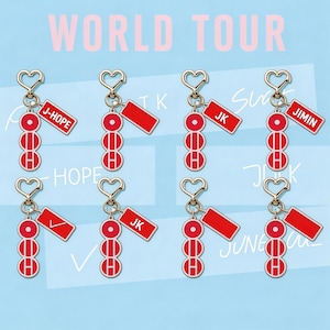 May include: Keychains with a heart-shaped clasp and a red pendant with a name tag. The keychains have a series of red circles and a red rectangular tag with names like "J-HOPE", "JK", and "JIMIN". The words "WORLD TOUR" are in the background.