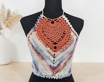 Puede incluir: Top halter de ganchillo hecho a mano en una variedad de colores, incluyendo naranja, morado y crema. El top presenta un diseño único con un motivo central naranja y un patrón de rayas. Se muestra en un maniquí negro.