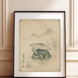 May include: A framed print featuring a dark green ink illustration of a turtle walking in the rain while holding a small umbrella. The artwork includes stylized mountains, tall grass, and vertical rain lines on a textured beige background.