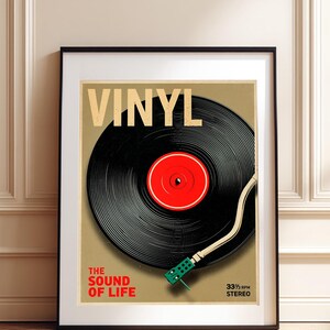 Puede incluir: Póster enmarcado con un disco de vinilo negro con centro rojo, brazo fonocaptor blanco y cartucho verde. La palabra "VINYL" en la parte superior, con "THE SOUND OF LIFE" y "33 1/3 RPM STEREO" debajo.