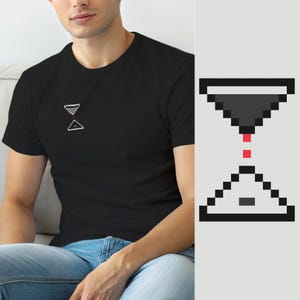 Puede incluir: Una camiseta negra de manga corta con un pequeño gráfico de reloj de arena pixelado en el pecho izquierdo. El diseño del reloj de arena consta de una sección superior gris oscuro, una sección inferior gris claro y dos cuadrados rojos.