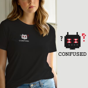 Peut inclure: Un t-shirt noir à manches courtes avec un petit graphique en pixel art sur la poitrine gauche. Le motif représente une tête de robot carrée aux yeux rouges, avec un point d'interrogation de chaque côté et le mot CONFUSED écrit en dessous.