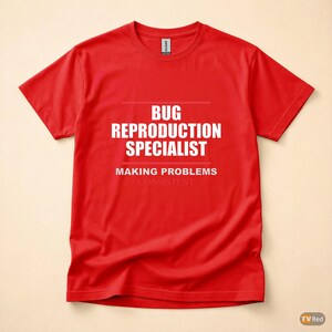 Op de afbeelding: Rood t-shirt met witte tekst. De tekst luidt "BUG REPRODUCTION SPECIALIST" boven "MAKING PROBLEMS CONSISTENT". Het shirt is effen rood van kleur en heeft korte mouwen.