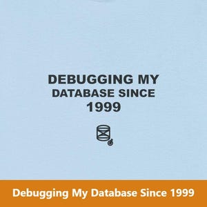 May include: Light blue t-shirt with the text "DEBUGGING MY DATABASE SINCE 1999" in black. Below the text is a graphic of a database icon. The shirt is a casual wear item.