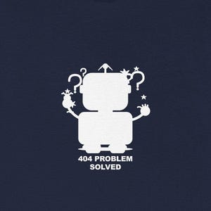 May include: Navy blue t-shirt with a white graphic of a robot with question marks and stars. The text "404 PROBLEM SOLVED" is below the robot. The shirt is made of a soft material.