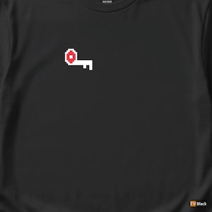 May include: Black t-shirt featuring a pixelated key design in red and white. The key graphic is positioned on the upper left side of the shirt. The shirt is made of a heavy cotton material.