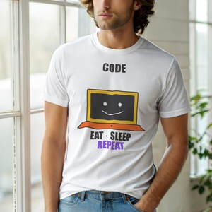 May include: White t-shirt with the text "CODE" above a smiling laptop graphic. Below the laptop, the text reads "EAT • SLEEP • REPEAT" in black and purple. The shirt is a casual wear item.
